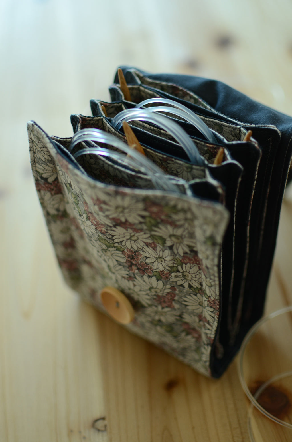 Interchangeable knitting needle storage with a zipper pocket