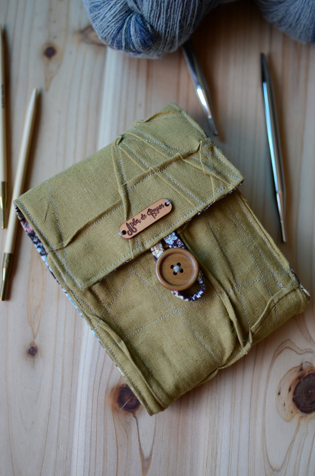 Interchangeable knitting needle storage with a zipper pocket